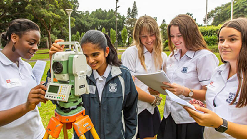 Group of school students using surveying equipment