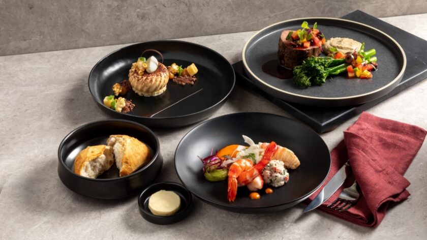 Image of a 3 course plated dinner from the Seasoned by Queensland menu. Entree - Queensland rock pool, Moreton Bay bugs, king prawn and spanner crab. Main - Pan seared barramundi, creamy polenta, fennel salad and confit tomatoes. Dessert - Roasted corn creme catalana, caramelised banana, dulce de leche, caramel puffed rice