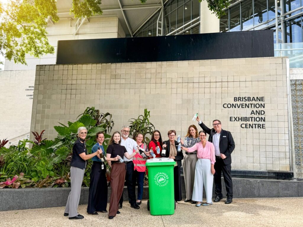 Group photo of the BCEC Corporate Social Responsibility Team putting 10c containers and bottles into a green Containers for Change bin