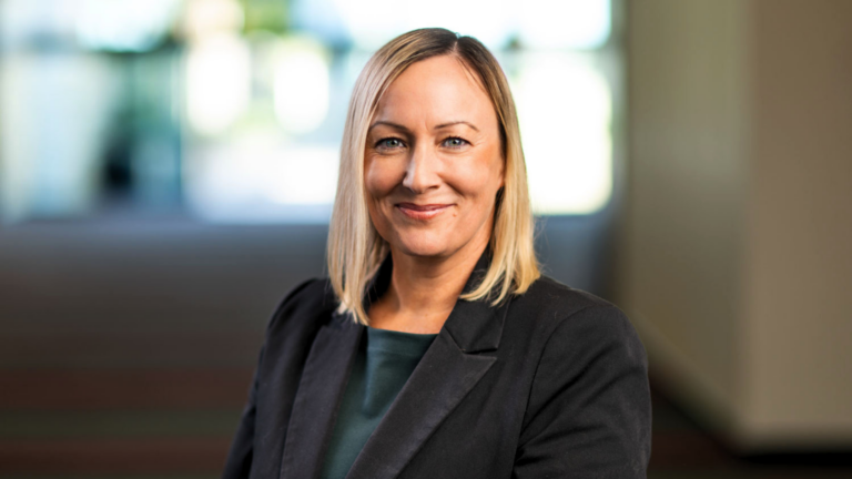 Website Featured Image 2 is a smiling woman in a black blazer, her blonde hair framing her face.